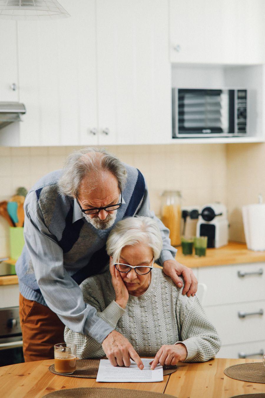 Senior couple reading planning documents at a kitchen table