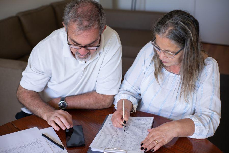 Senior couple reviewing documents and online banking at home